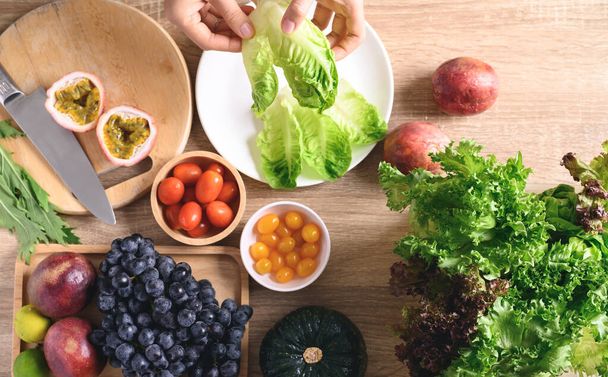 Manos de mujer preparando frutas y verduras frescas para la cocina vegana en mesa de madera, Comida saludable, Vista superior de la mesa - Foto, Imagen