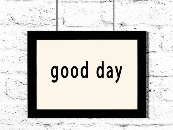 Μαύρο ξύλινο πλαίσιο με επιγραφή καλή ημέρα κρέμεται σε λευκό τοίχο τούβλο  - Φωτογραφία, εικόνα