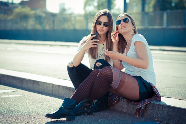 dos hermosas mujeres jóvenes utilizando el teléfono inteligente
 - Foto, imagen