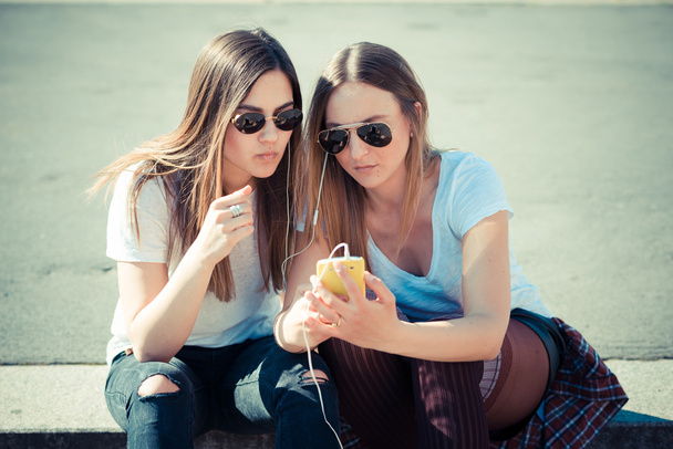 két gyönyörű fiatal nő segítségével okos telefon - Fotó, kép