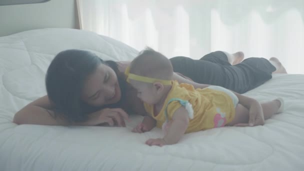 Молода азіатська мати цілує щоку маленької дівчинки з телятиною на ліжку в спальні, мама любить новонароджених і догляд, мати з виразом з дитиною разом, мати і дочка, концепція сім'ї
. - Кадри, відео