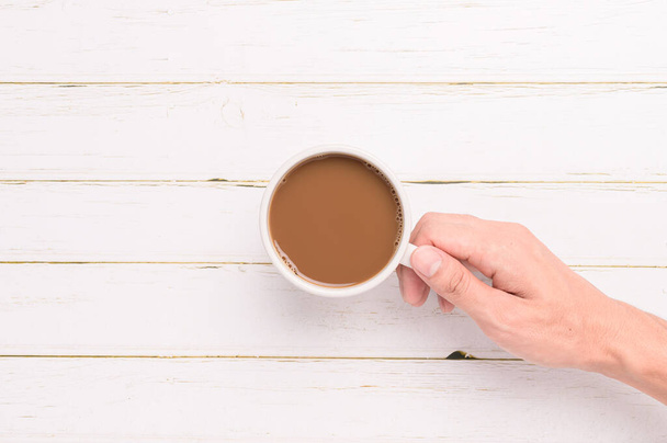 Рука держит кофейную кружку на деревянном фоне - Фото, изображение