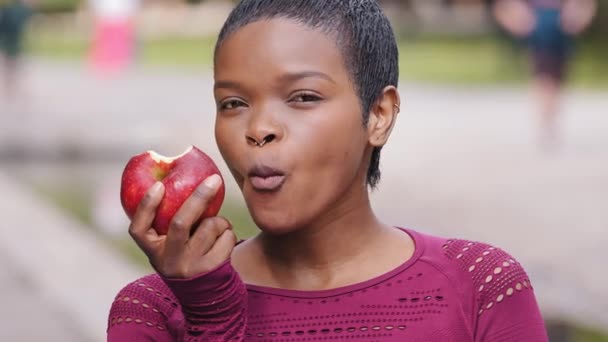 Όμορφη νεαρή αθλητική μαύρο χιλιετή κορίτσι με χαρά να τρώνε νόστιμο μήλο, επιλέξτε υγιεινά τρόφιμα, το βάρος ελέγχου. Ευτυχής μικτή φυλή θηλυκό θέτει το παράδειγμα για τη νεολαία προωθεί υγιή τρόπο ζωής - Πλάνα, βίντεο