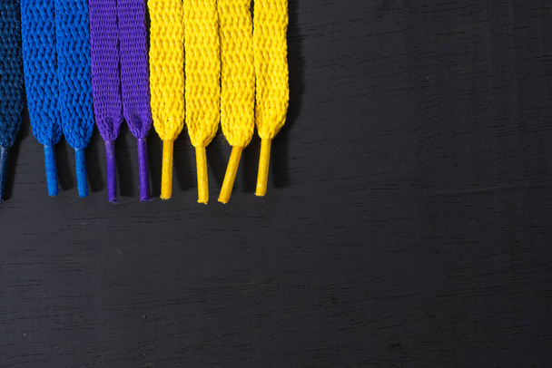 background of colored shoelaces on black wood, arranged vertically, concept of perfection, leaving space for advertising text - Photo, Image