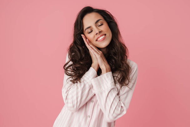 Happy beautiful woman smiling while posing with eyes closed isolated over pink background - Φωτογραφία, εικόνα