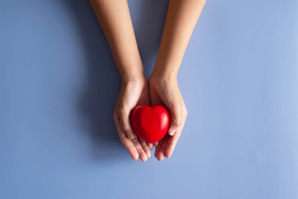 Hands people holding red heart model on blue background,World heart day concept,Top view,Copy space for text - Fotó, kép