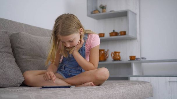 Děvče školního věku je doma a používá k hraní a kreslení tablet. Vzdálený trénink bez opuštění domova. Vývoj schopností u dětí. - Fotografie, Obrázek