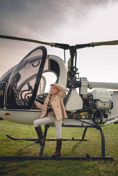 Blonde tween girl near helicopter looking into distance - Фото, изображение