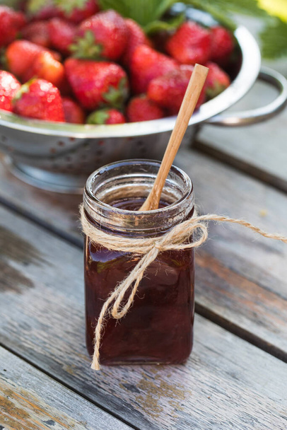 Strawberry jam in a jar on a wooden board. Fermented berries. - Foto, afbeelding