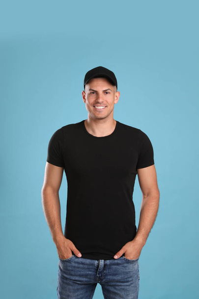 Happy man in black cap and tshirt on light blue background. Mockup for design - Фото, изображение