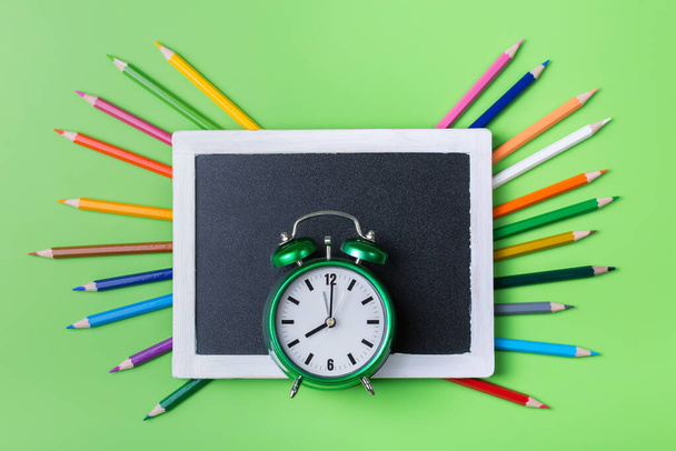 Colourful rainbow pencils and alarm clock on lime green background - Fotografie, Obrázek