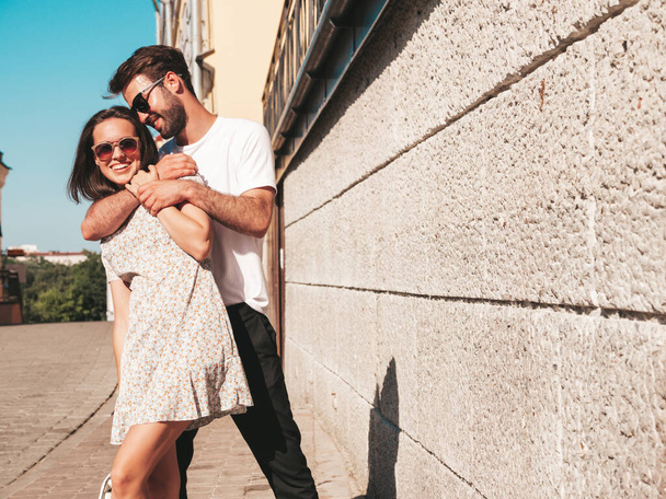 Smiling beautiful woman and her handsome boyfriend. Woman in casual summer clothes. Happy cheerful family. Female having fun. Couple posing on the street background in sunglasses.Hugging each other - Foto, immagini