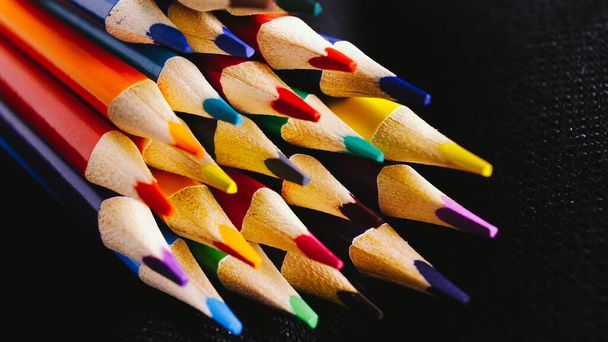 Abstracte achtergrond voor creativiteit. Veel gekleurde potloden op een donkere achtergrond. - Foto, afbeelding