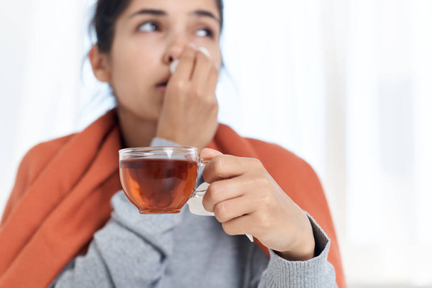 žena pokrytá přikrývkou studenou pilulku léčba šálek čaje v rukou - Fotografie, Obrázek