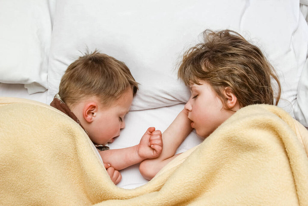 Prachtig slapende kinderen op het bed 's nachts op de kamer achtergrond - Foto, afbeelding