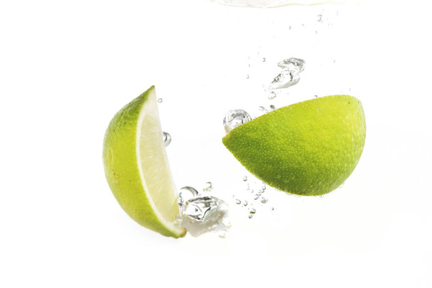 νερό πιτσιλίσματος ασβέστη και λεμονιού που απομονώνεται σε λευκό φόντο - Φωτογραφία, εικόνα