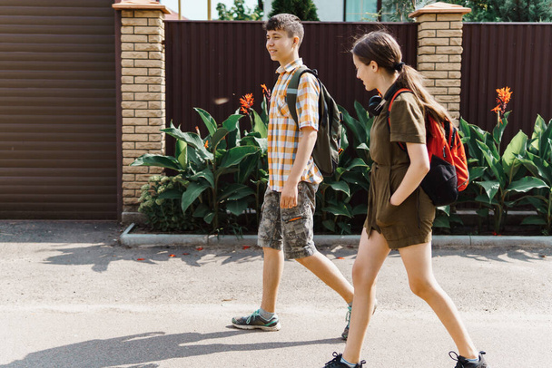 két tinédzser fiú és lány megy végig az utcán az iskolába, az oktatásba és vissza az iskolába koncepció - Fotó, kép