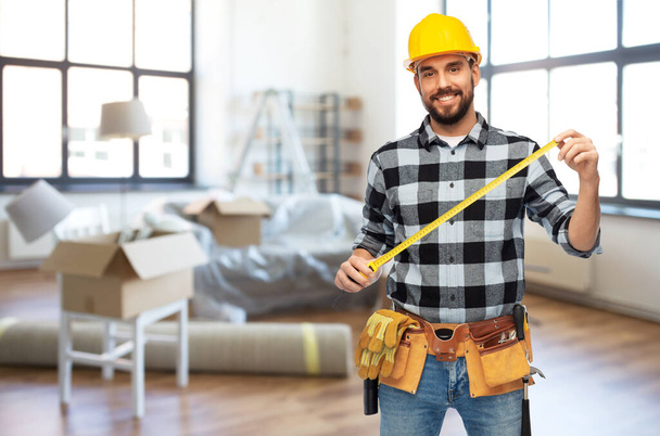 happy male builder in helmet with ruler at home - Photo, Image