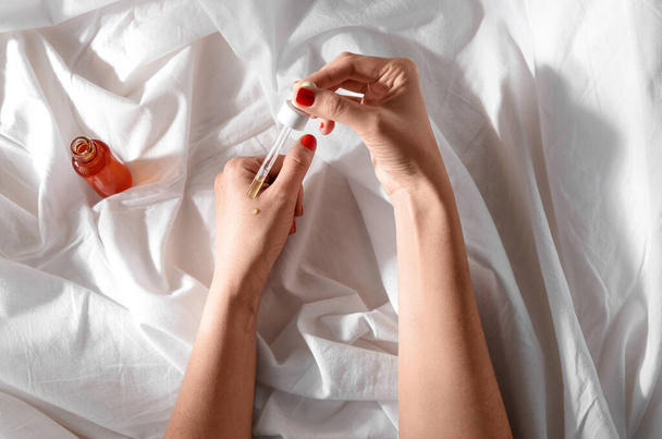 female hands with dropper applying serum to skin - 写真・画像