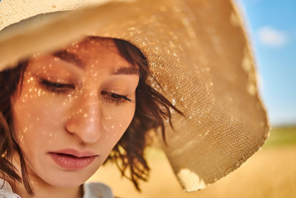 A close portrait of a woman in a summer hat - 写真・画像