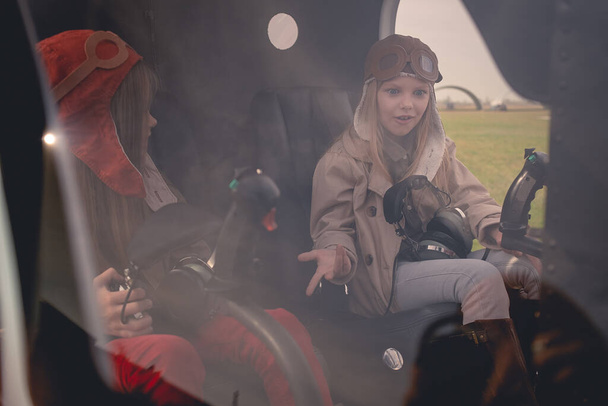 Yllättynyt teini tyttö istuu ohjaajan istuimella helikopterin ohjaamossa ystävän kanssa - Valokuva, kuva