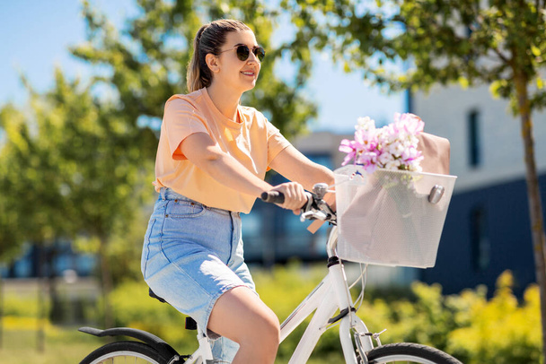 woman with flowers in bicycle basket in city - Φωτογραφία, εικόνα