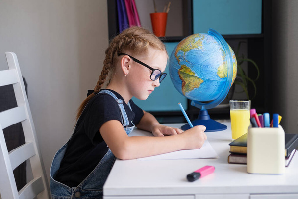 Serious caucasian redhead girl with eyeglasses studying at home, make homework - Foto, imagen