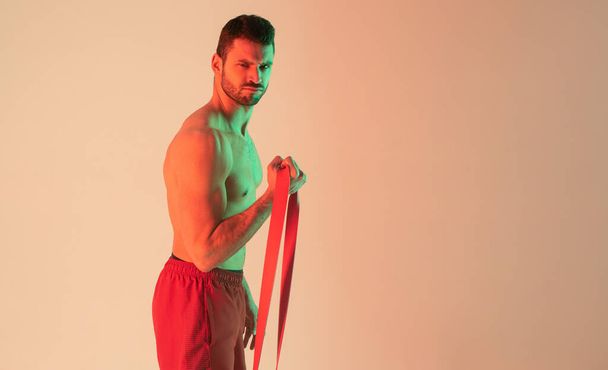 Strong sportsman do exercise with resistance band - Photo, Image