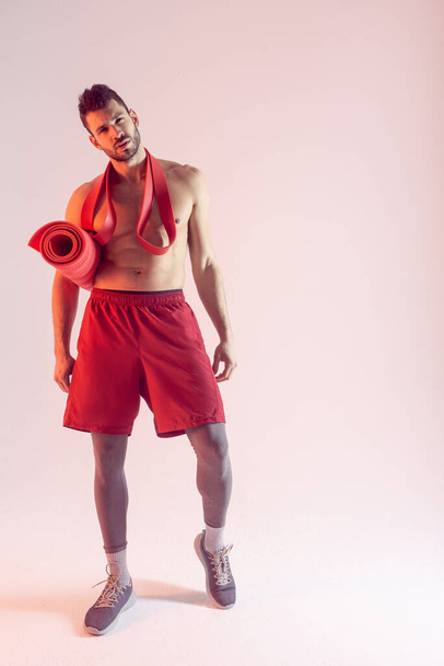 Sportsman avec bande de résistance et tapis de fitness - Photo, image
