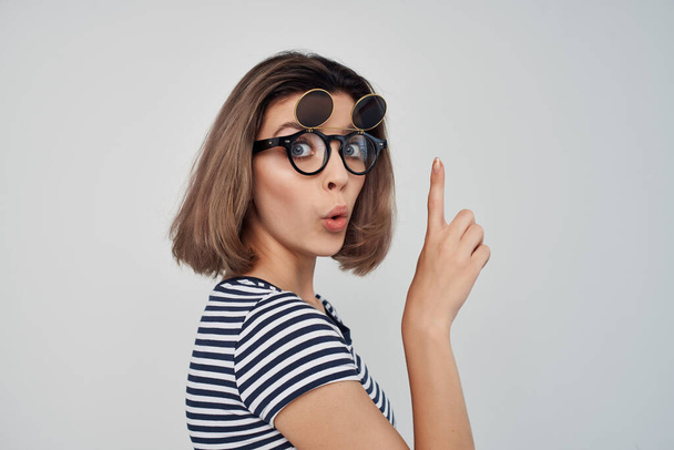 alegre mujer de moda en camiseta a rayas con gafas apuntando  - Foto, Imagen