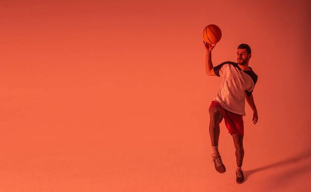 Молодой европейский спортсмен играет в баскетбол в студии - Фото, изображение