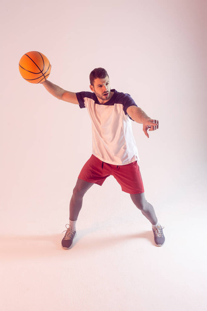 Young european sportsman play basketball in studio - Foto, afbeelding