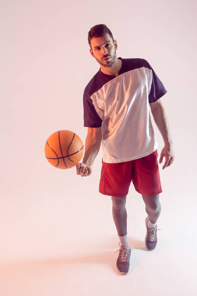 Jovem desportista girando bola de basquete no dedo - Foto, Imagem