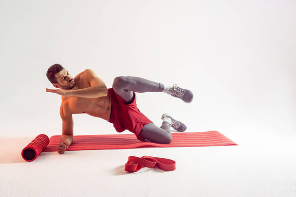 Sportsman train abdominal muscles on fitness mat - Фото, изображение