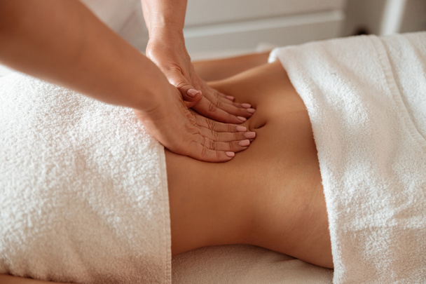 Masseuse massaging female client abdomen in spa salon - Fotó, kép