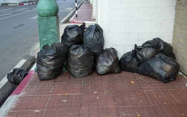 Plusieurs sacs noirs d'ordures ont été placés sur le trottoir. - Photo, image