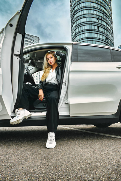 business portrait of girl in an expensive car on the background of the city - Фото, изображение