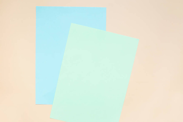 Fogli bianchi di carta blu e gialla su sfondo beige. Layout, spazio di copia. - Foto, immagini
