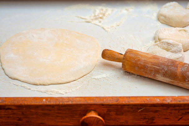 La pâte finie repose sur la table coulissante à côté du rouleau. - Photo, image