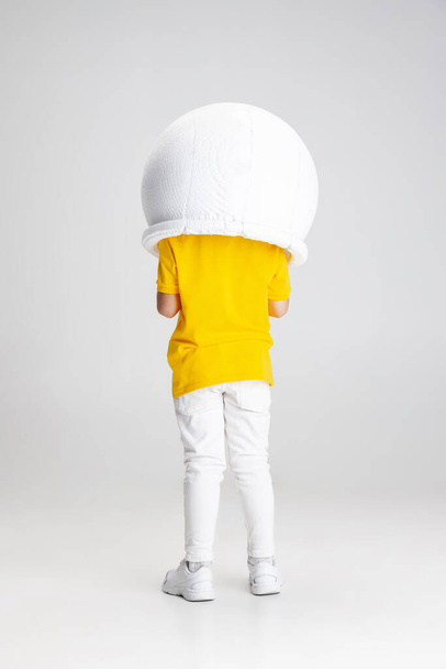 Retrato de menino pré-escolar posando em capacete isolado sobre fundo de estúdio branco. Visão traseira - Foto, Imagem