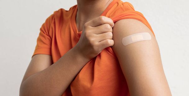 Азиатка показывает гипс на плече после вакцинации против Ковида-19. Концепция кампании против коронавируса. - Фото, изображение