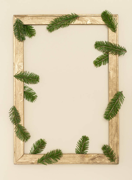 Christmas background with golden wooden decorative frame with green fir branches, New Year holiday decoration with copy space, greeting card, invitation for winter celebration events. - Fotografie, Obrázek