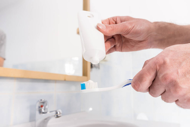 Person putting toothpaste on toothbrush. Teeth hygiene care, clean oral brush essentials concept. - Fotografie, Obrázek