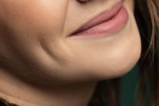 Close-up lábios bonitos femininos, boca isolada sobre fundo estúdio verde escuro. Beleza natural, bem-estar, pele bem cuidada, conceito de cosméticos à base de plantas - Foto, Imagem