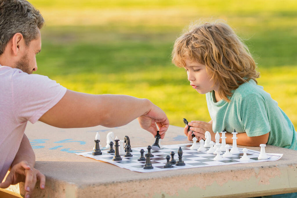 famiglia felice di papà e figlio bambino che gioca a scacchi sul tavolo nel parco all'aperto, torneo di scacchi - Foto, immagini
