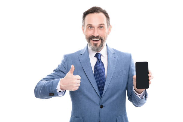 счастливый бизнесмен представляет смартфон изолирован на белом шоу большой палец вверх копировальное пространство, презентация. - Фото, изображение