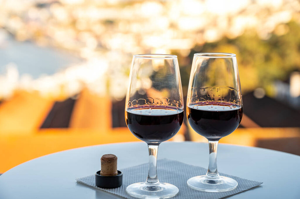 Ochutnávka různých opevněných zákusků rubínu, žlutohnědých portských vín ve sklenicích s výhledem na řeku Douro, porto chaty Vila Nova de Gaia a město Porto, Portugalsko, při západu slunce - Fotografie, Obrázek