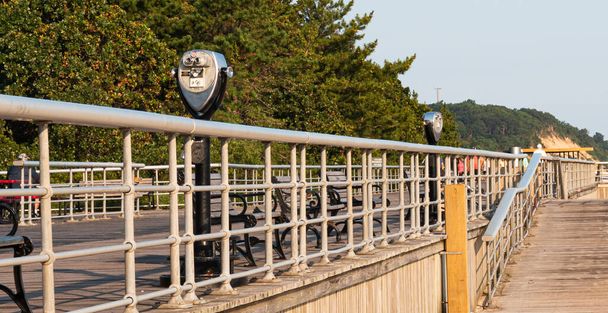 Pohled z pláže na západ na dvoumincovní dalekohled na promenádě ve Státním parku Sunken Meadow v New Yorku. - Fotografie, Obrázek