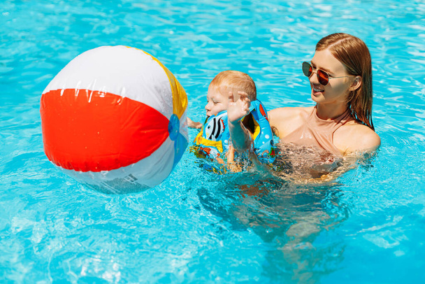 Happy family in the pool, have fun in the water, mom with child enjoying the water park, beach resort, summer vacation, vacation concept - 写真・画像