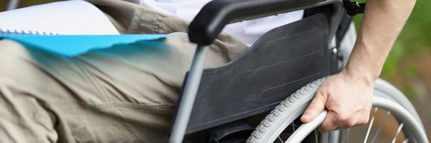 Άντρας σε αναπηρική καρέκλα κρατά τροχό με το χέρι του - Φωτογραφία, εικόνα
